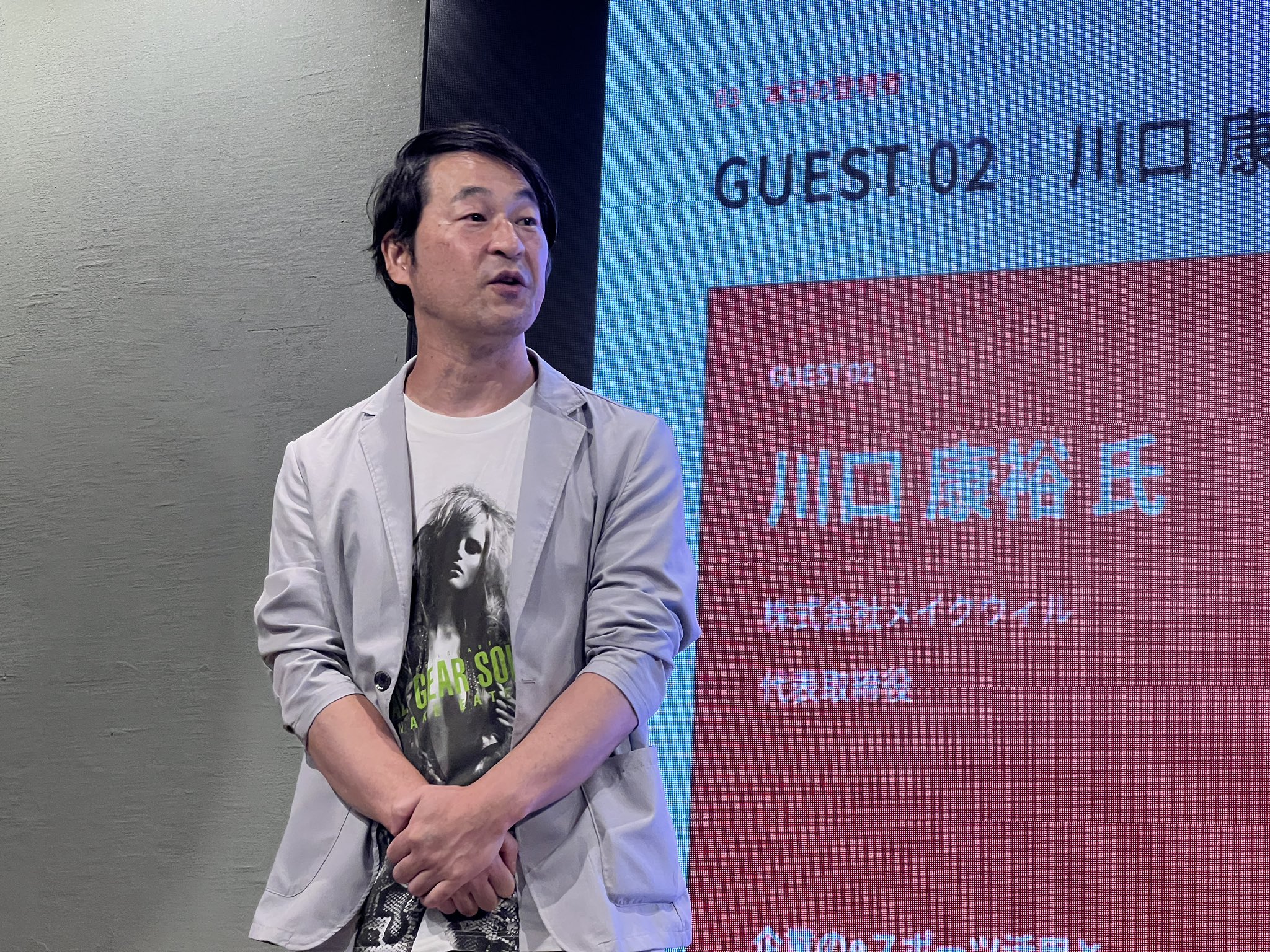 メイクウィルの川口康裕さんが当日のスクリーン前で登壇する様子