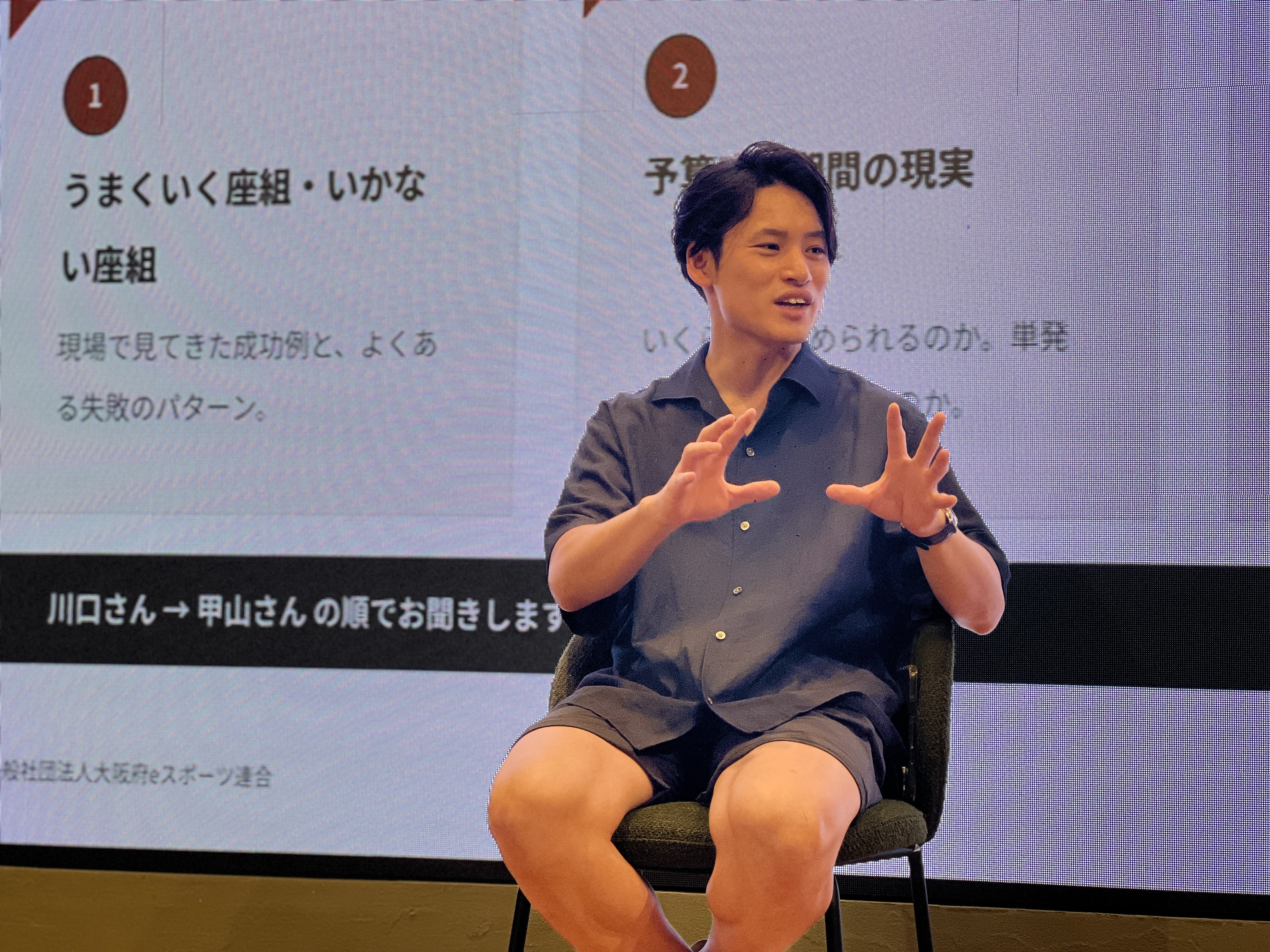 第1回勉強会で、スクリーンの前に座り身振りを交えて話す登壇者